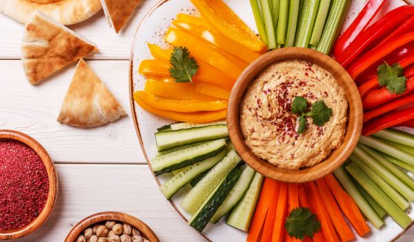 hummus met gezonde snacks, zoals wortels, papraika en bleekselderij