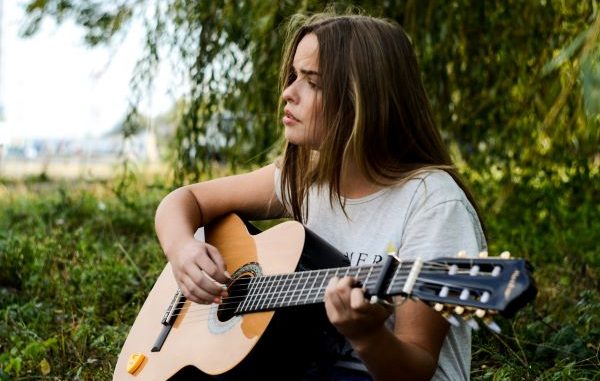 vrouw speelt muziek op gitaar in de natuur