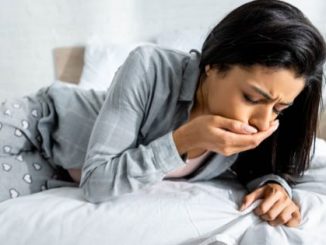 vrouw is misselijk op bed door norovirus symptomen
