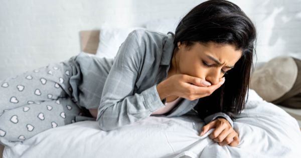 vrouw is misselijk op bed door norovirus symptomen