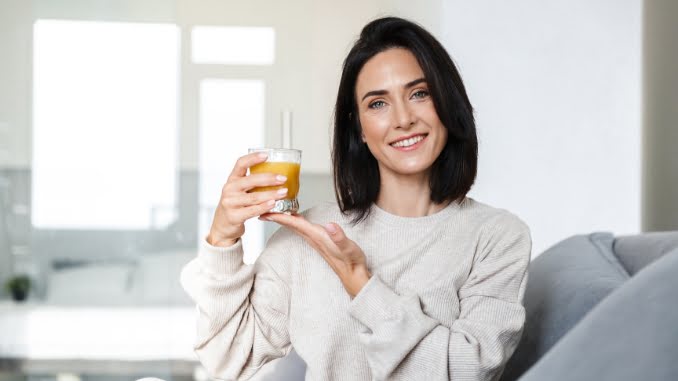 vrouw houdt een glas sinaasappelsap